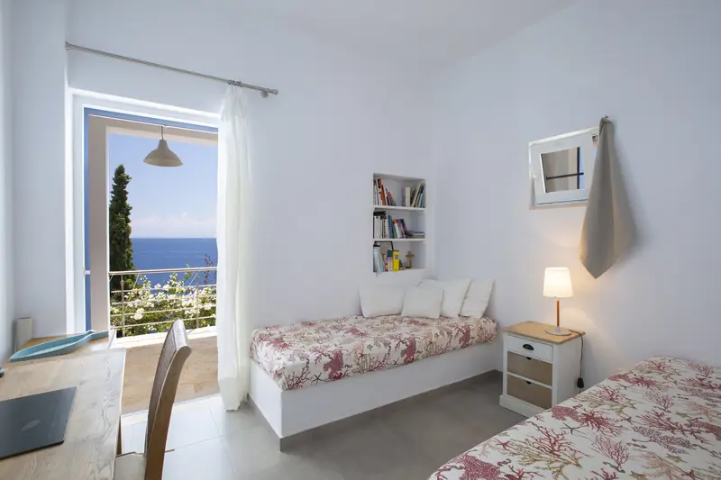 Twin bedroom with white linen and a window onto the cypress