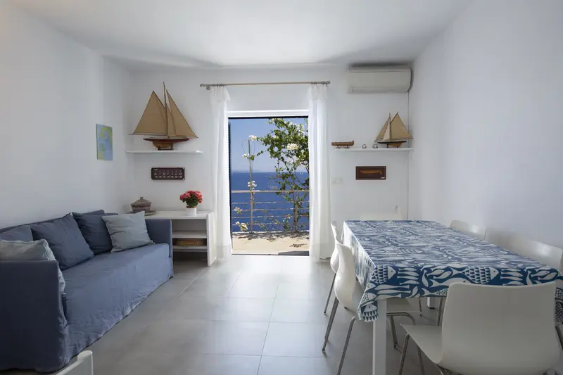 Sitting room with white walls, beamed ceiling and doors to the garden